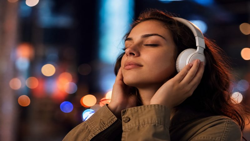 Creator listening to music with headphones in an urban night setting